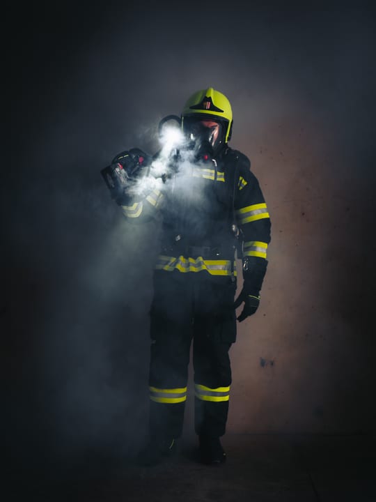 Feuerwehrmann in voller Schutzausrüstung mit Helmlampe im Rauch